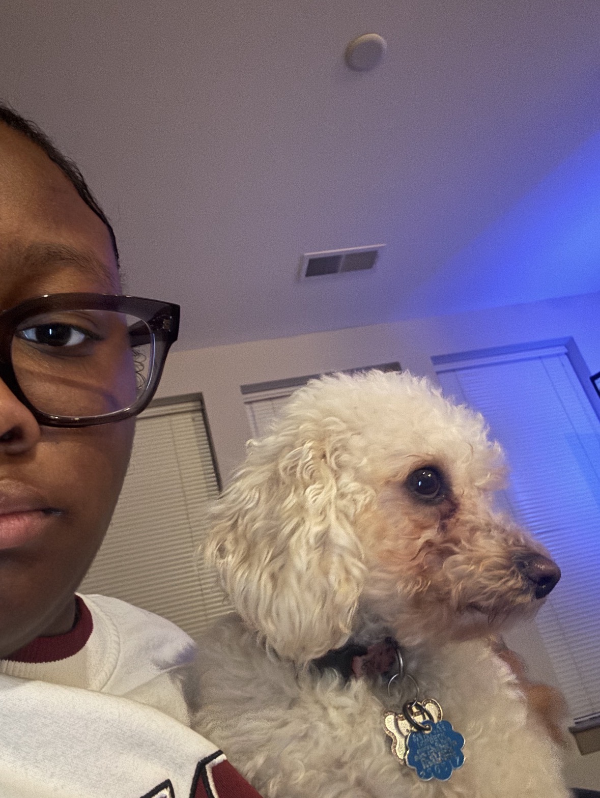 Mya holding a white poodle mix at home